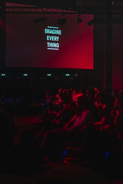 Audience watching a presentation on a large screen with the message "Imagine Everything".