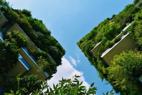 Modern eco-friendly buildings with lush green roofs and walls in an urban setting.